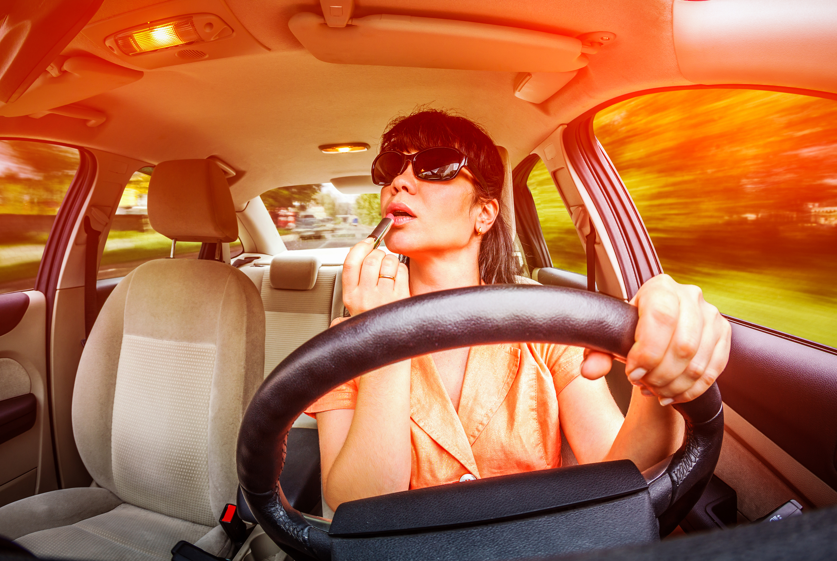 Women make up lips at the wheel the car, not stares on the road